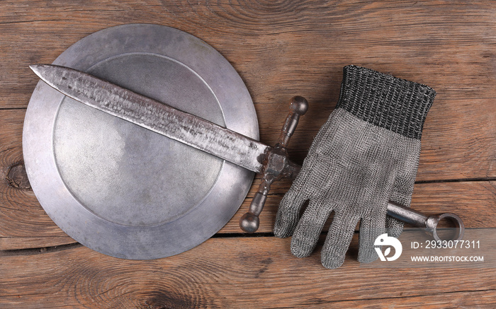 Knight armor, sword and shield on wooden background