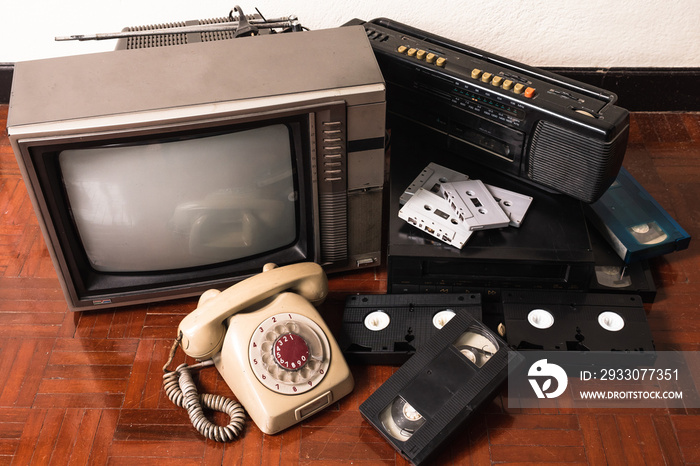 Old telephone and obsolet electronic equipment on wooden floor.