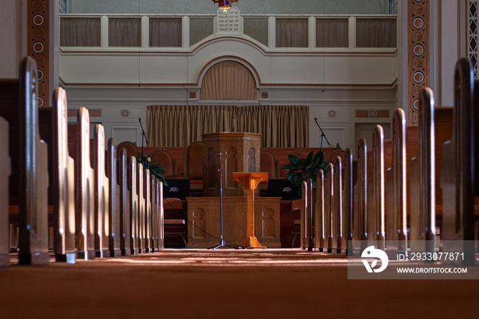 medium wide shot of an empty church sanctuary with afternoon sunlight pouring in creating shadows down the aisle to the front of the church