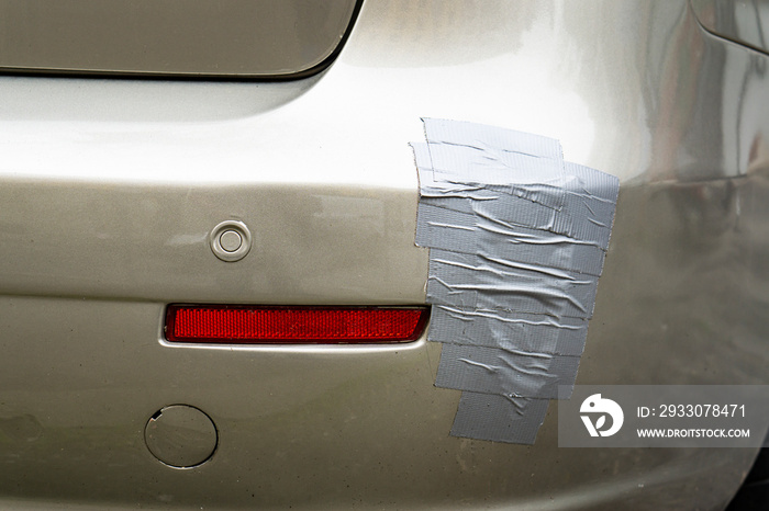 back side of a car automobile, broken car bumper with scotch tape layering stuck covering the scar of dent scratch broken parts, concept of automobile car service fixing repairing in for inspection