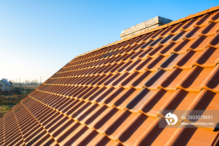 Overlapping rows of yellow ceramic roofing tiles covering residential building roof.