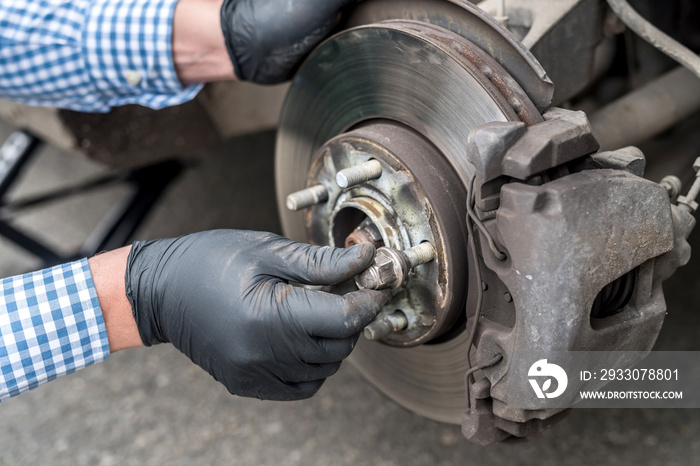 Hands of mechanic repairing brake disk of a car