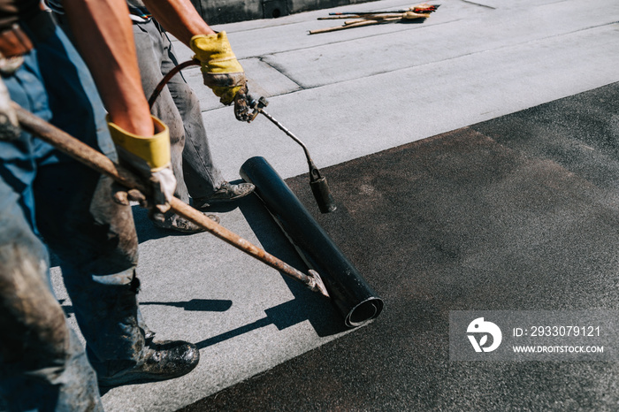 Bituminous membrane waterproofing system details and installation on flat rooftop. Professional construction worker  installing and waterproofing flat roof at house construction site.