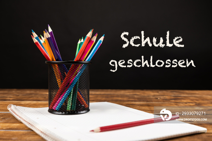 colored pencils with paper and german text schule geschlossen, in english school closed