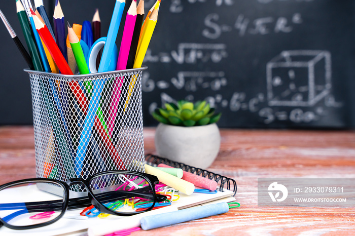 Stationery, glasses and a blackboard in the background with mathematical formulas. Back to school. Close-up. Selective focus.