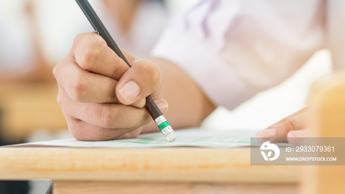 Students holding pencil eraser while taking exams, examination room, writing answer optical form in high school classroom, view of having test in class on seat rows, Education  literacy concept.