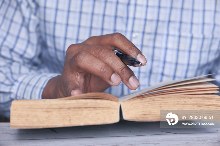 close up of man reading a book on table