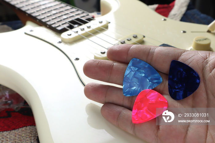 guitar picks are in the right hand with background of vintage ivory color electric guitar during the concert music performance