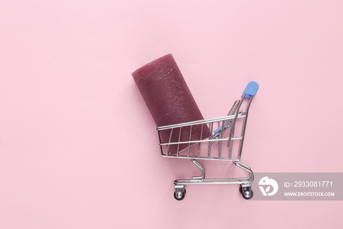 Supermarket trolley with candles on pink background