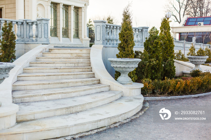 Luxury mansion with marble staircase, white stone balustrade and park garden. Large house of royal palace style