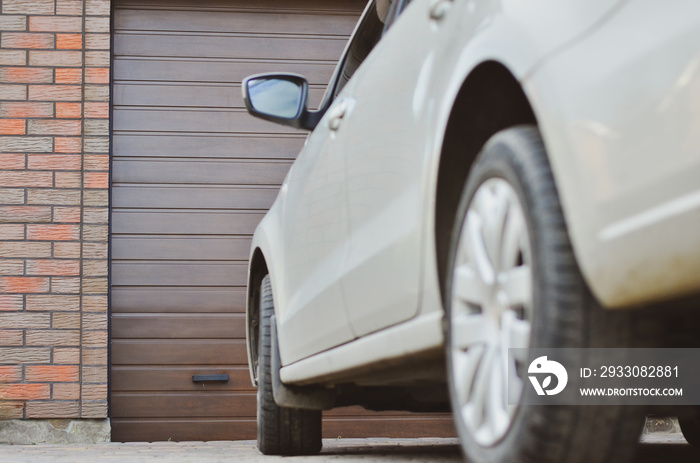 Part of a car parked in front of the garage door