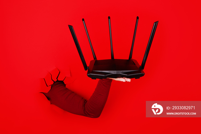 black wi fi router on hand over red background