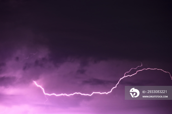 Lightning thunderstorm flash over the night sky, purple