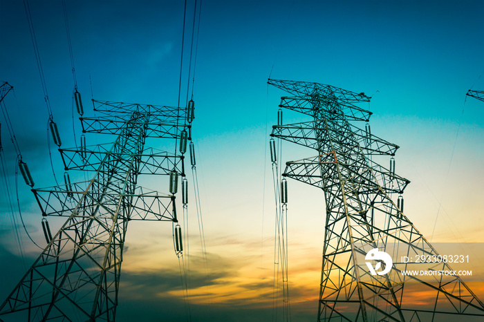 Sun setting behind the silhouette of electricity pylons