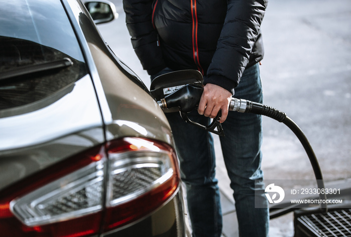 Man refueling his car in the gas or filling station by naphtha or oil fuel, fueling process