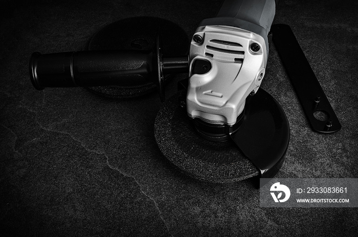 Low Key view of an angle grinder on concrete floor with accessories