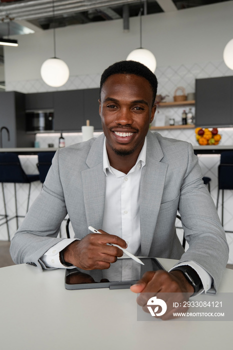 Portrait of young businessman using digital tablet in office cafeteria