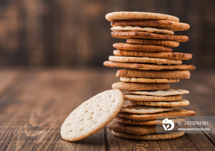 Stack of various organic crispy wheat, rye and corn flatbread crackers with sesame and salt on wooden background. Space for text