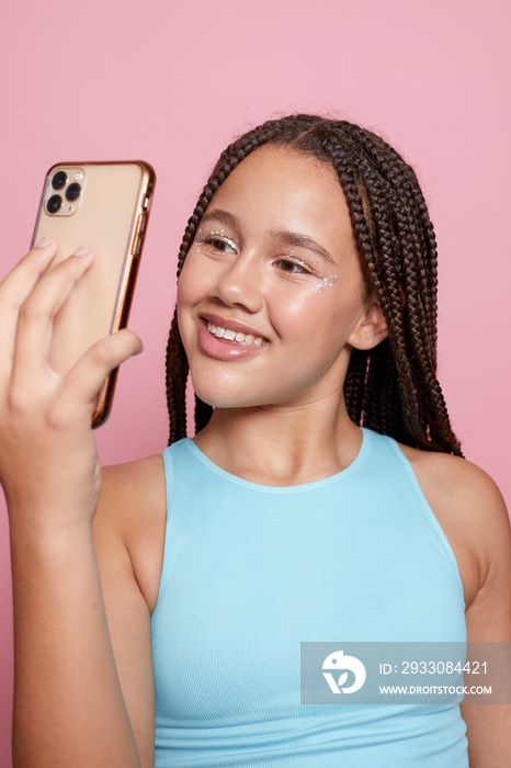 Studio shot of smiling girl with braids taking selfie