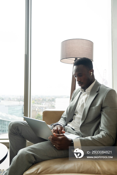 Young businessman sitting on sofa and using laptop