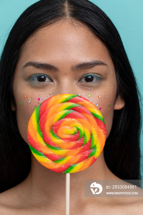 Woman holding colorful lollipop in front of face