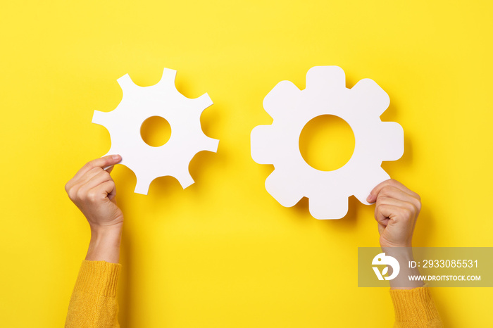 gear symbol in hands over yellow background