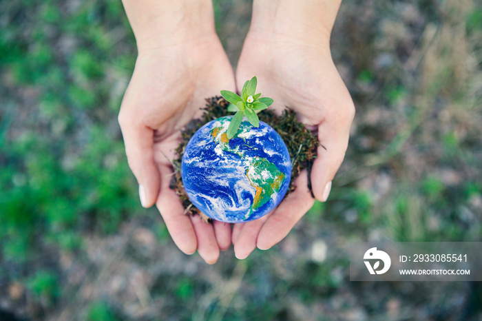 Women holding planet in hands against green background. World environment day concept. Elements of this image furnished by NASA