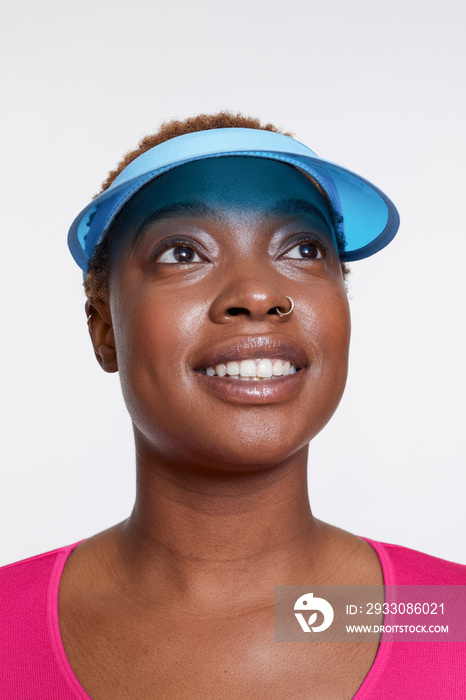 Studio portrait of smiling woman wearing blue sun visor