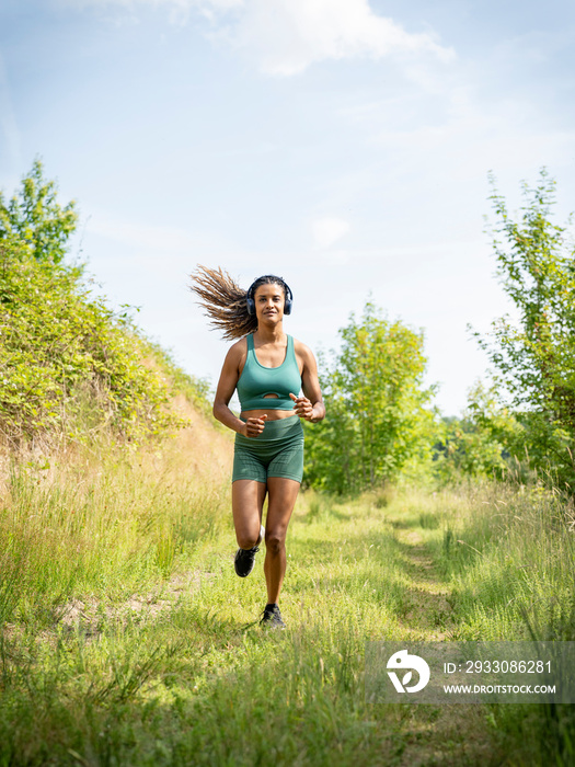 Woman running in meadow on sunny day