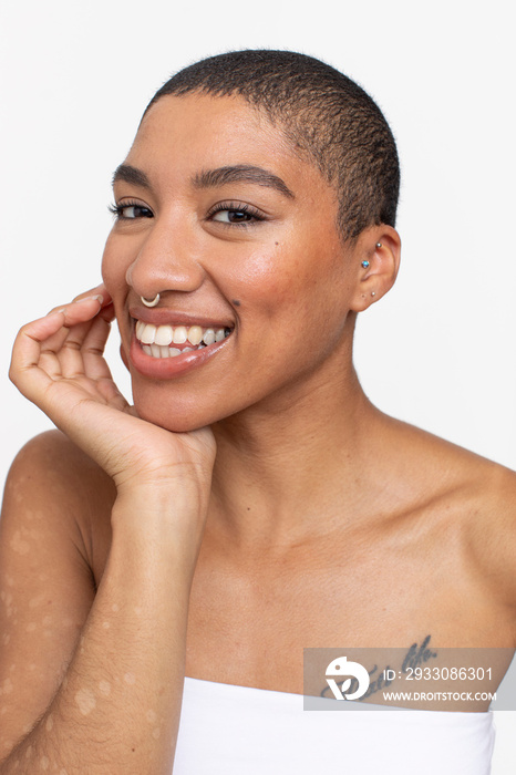 Studio portrait of smiling woman with short hair and nose ring