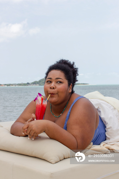 Young woman drinking cocktail and relaxing near bay