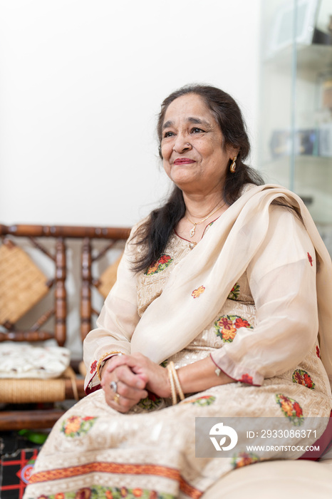 Portrait of cheerful senior woman sitting in living room