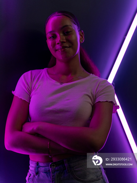 Portrait of young woman against wall with neon lights