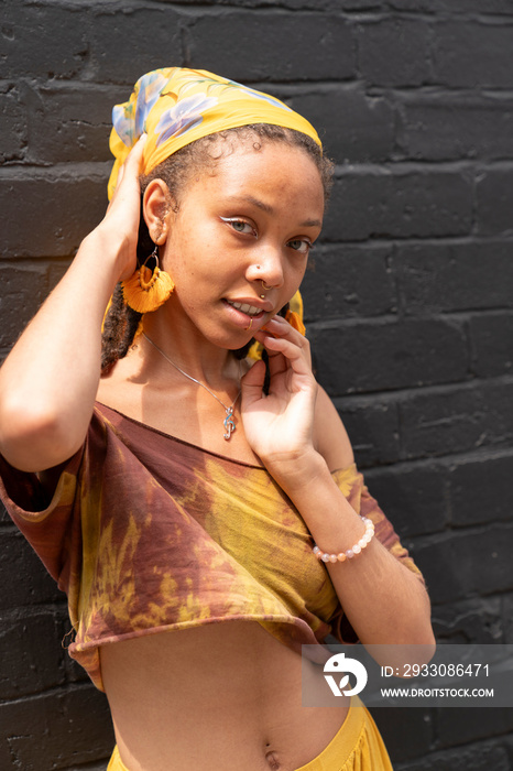 Portrait of young woman standing against brick wall