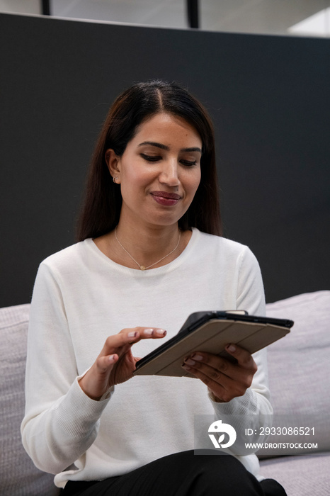 Woman sitting on sofa and using digital tablet