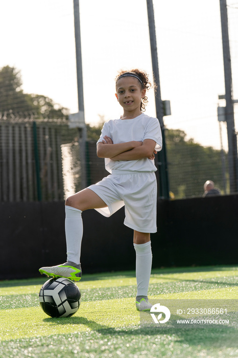 Portrait of girl (6-7) with ball on soccer field