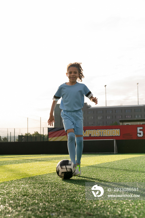 Girl (6-7) playing soccer on soccer field