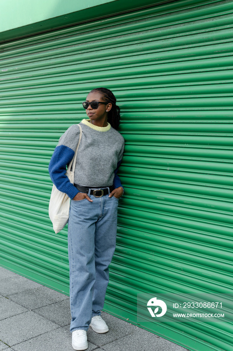 Young stylish woman standing in front of green door