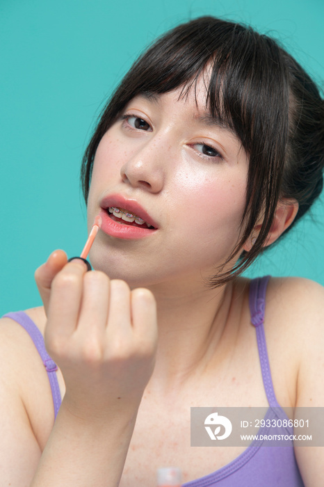 Studio portrait of girl applying lip gloss