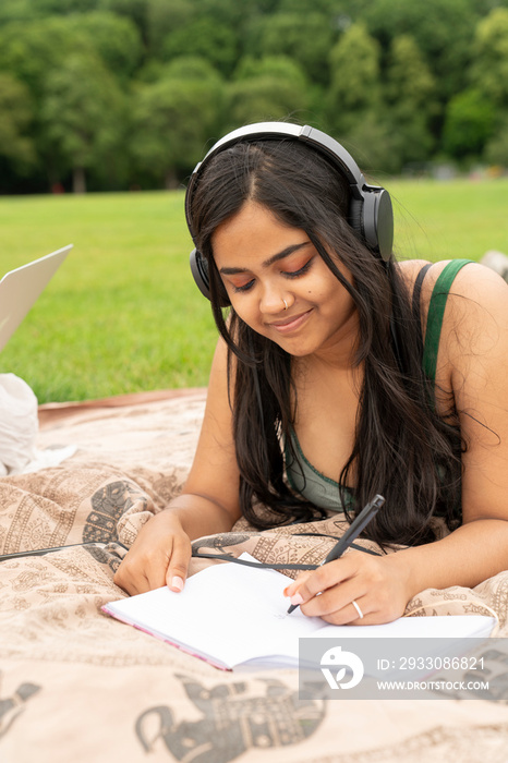 Smiling woman writing diary at picnic in park