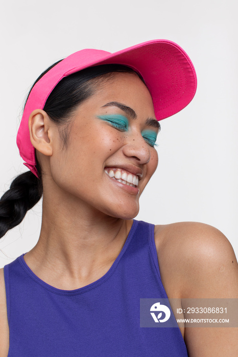 Portrait of smiling woman wearing blue makeup and sun visor