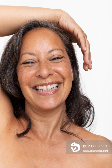 Studio portrait of smiling shirtless woman with hand on head