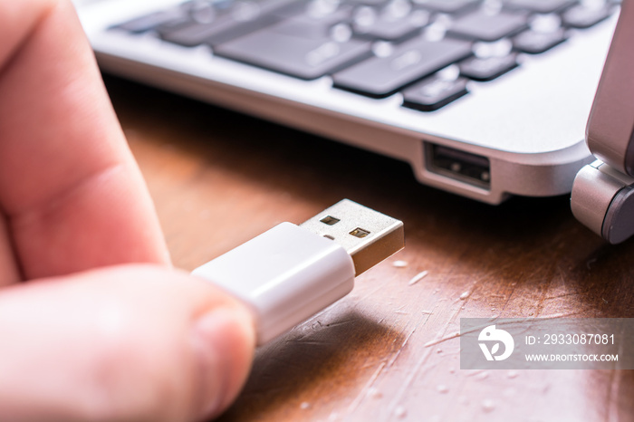 Male Hand Connecting A White USB Cable To The USB Port Of A Small Keyboard