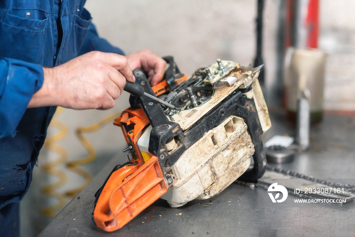 Mechanic repairing a chainsaw. Man repairing a chainsaw in workbench .