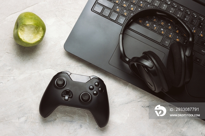 Top view of Gamepad, Laptop and Headphones, Apple on a White table with Сopy space. Gamers background concept