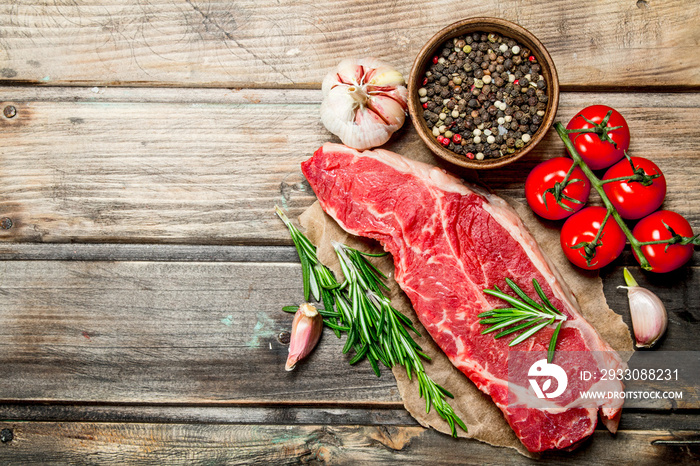 Raw steak with rosemary, tomatoes and aromatic spices.