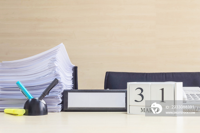 Closeup white wooden calendar with black 31 march word on blurred brown wood desk and wood wall textured background in office room view with copy space , selective focus at the calendar