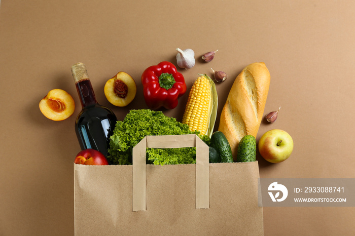 Bunch of mixed organic fruits, vegetables & greens, gourmet pile in full eco friendly shopping bag to reduce ecological footprint. Zero waste concept. Brown table background, copy space, close up.