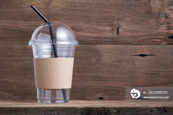 empty disposable cold coffee or drink cup have blank brown cardboard sleeve and straw on old wood shelf background