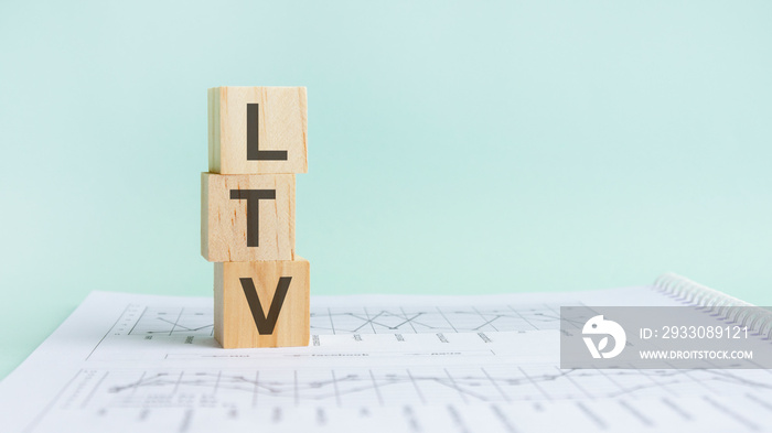 three wooden cubes with letters LTV on white paper with diagramm